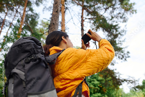 Venturing through a colorful forest, a young woman captures the radiant autumn foliage with her camera.