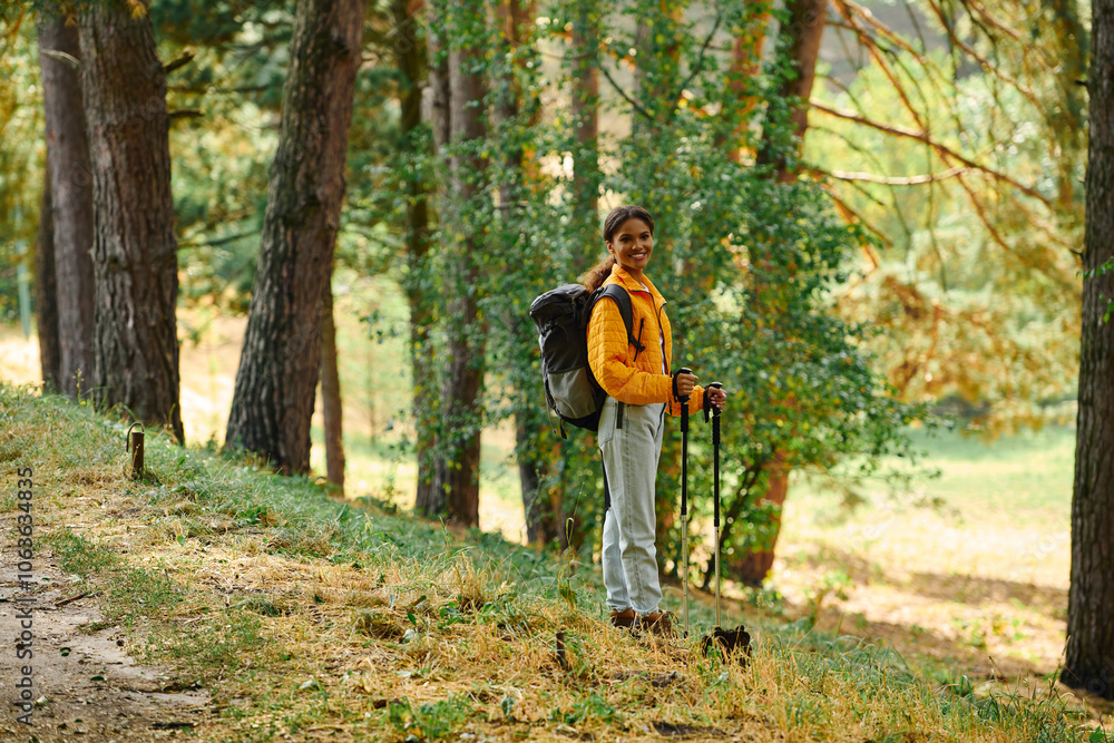 A young African American woman explores a beautiful forest, immersed in the autumn colors while hiking. A young African American woman explores a beautiful forest, immersed in the autumn colors while hiking.