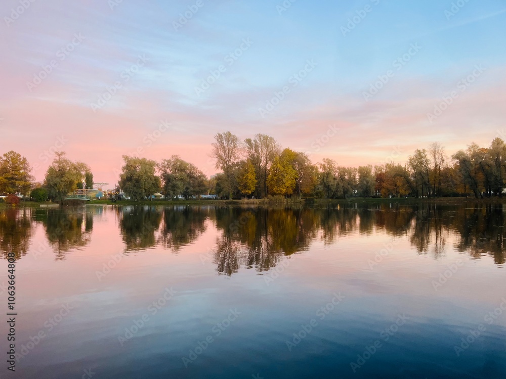 Beautiful tender twilights in the park, sky and trees reflection on the pond surface, evening lake in the park Beautiful tender twilights in the park, sky and trees reflection on the pond surface, evening lake in the park