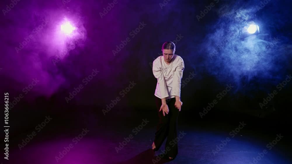 Mysterious female figure dancing in dark studio with smoke and purple lights. Attractive young woman moving in darkness, dance performance with energy of art and emotions, professional performer lady Mysterious female figure dancing in dark studio with smoke and purple lights. Attractive young woman moving in darkness, dance performance with energy of art and emotions, professional performer lady