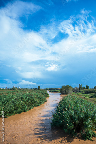 Muddy river flowing under cloudy sky after heavy rain photo