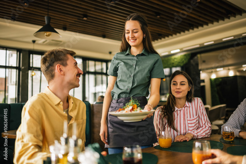 Fotografija Waitress brings out the first meal, which is caesar salad, to her guests in a restaurant