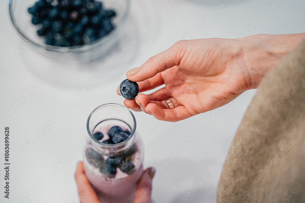 Close up of a woman making a smoothie with fruits and berries; selective focus. Healthy food concept.