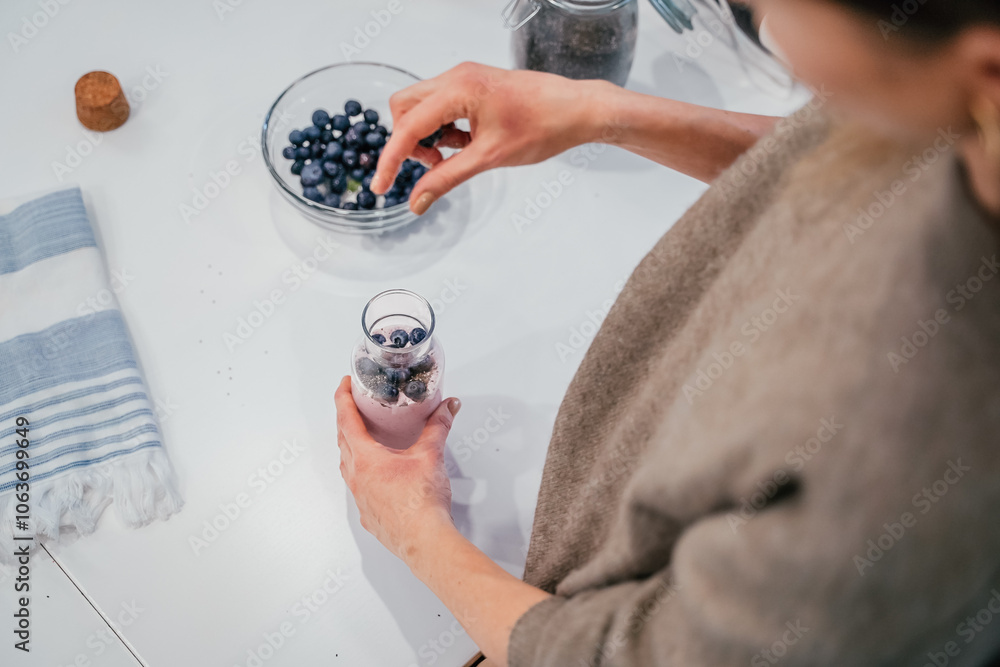 Close up of a woman making a smoothie with fruits and berries; selective focus. Healthy food concept.