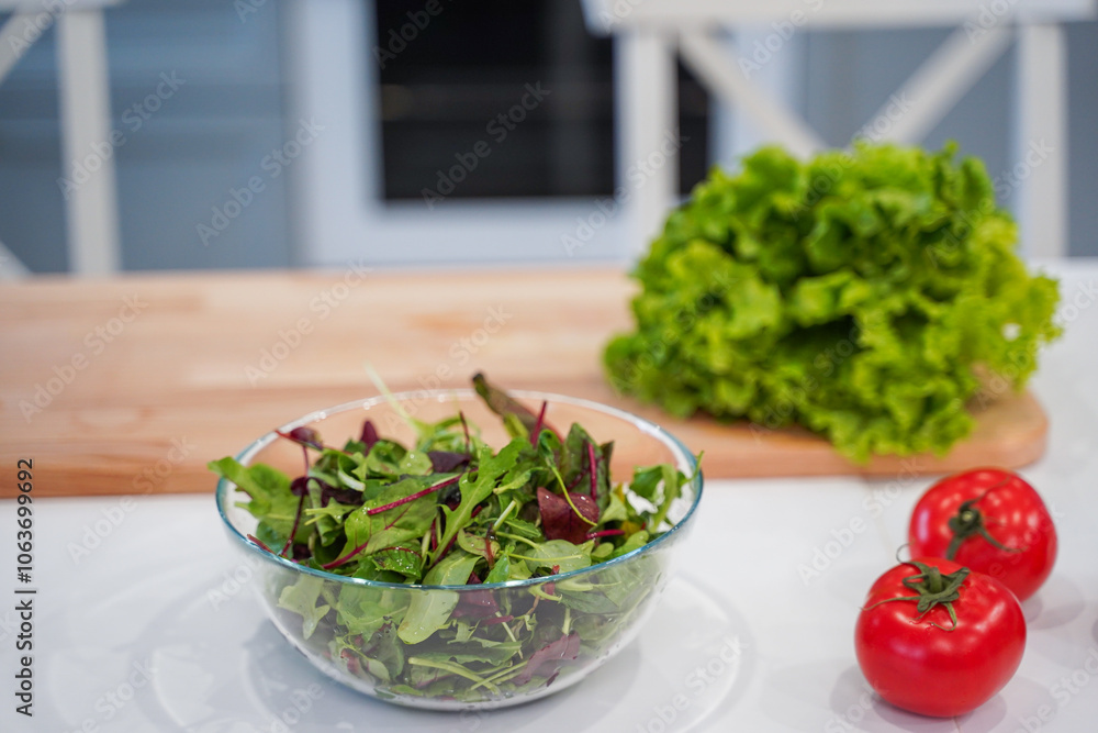 Full bowl of fresh green salad close up on a light table on a kitchen. Concept helpful and healthy food