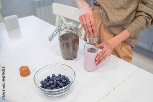 Close up of a woman making a smoothie with fruits and berries; selective focus. Healthy food concept.