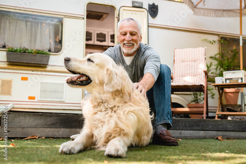 Active old senior man adventurer explorer playing with dog near trailer. photo