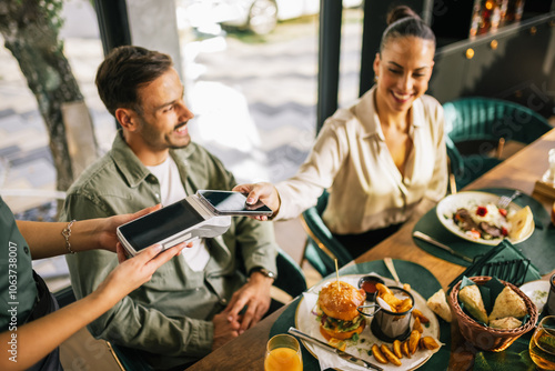 Fotografia People paying with contactless credit card in a restaurant.
