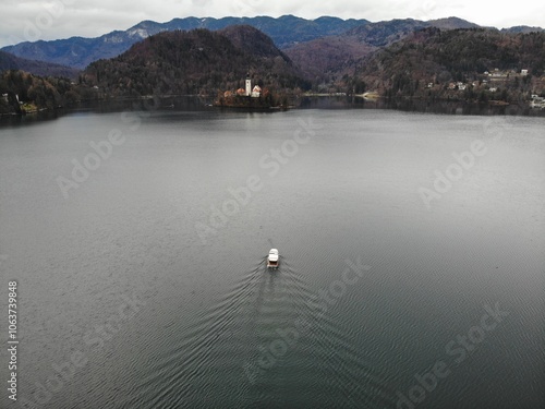 A photo of a boat is floating in a lake with mountains in the background photo