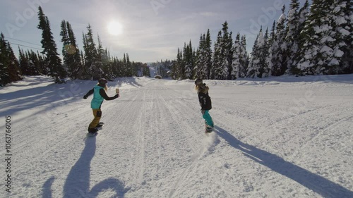 Two snowboarders going down hill together - slow motion photo