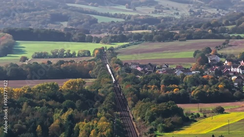 Drone video of an ICE train traveling through Germany in autumn. Vibrant fall foliage surrounds the tracks, highlighting the contrast between nature and modern rail travel. Drone move left