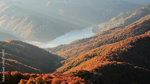 Amazing sunrise with moving sun rays over lake and red beech forest covers the mountains hills in the fall season. Ukrainian Carpathian mountains. UHD 4k timelapse