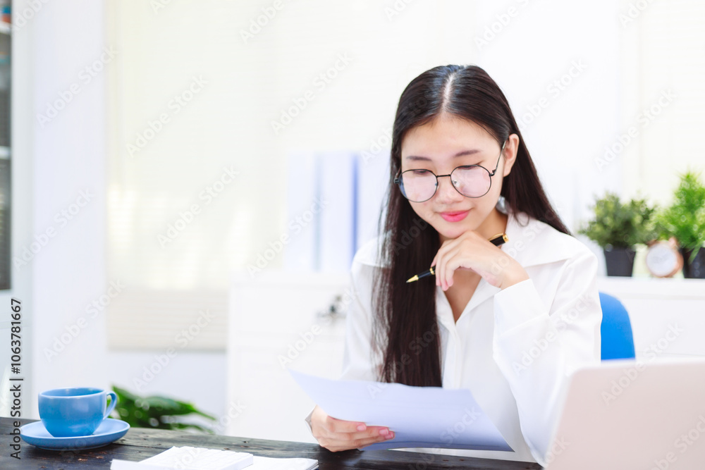 An Asian woman sits at her desk, surrounded by files , embodying dedication and professionalism in her work. An Asian woman sits at her desk, surrounded by files , embodying dedication and professionalism in her work.