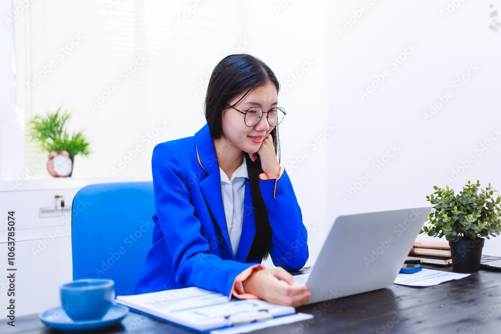 An Asian woman sits at her desk, surrounded by files , embodying dedication and professionalism in her work. An Asian woman sits at her desk, surrounded by files , embodying dedication and professionalism in her work.