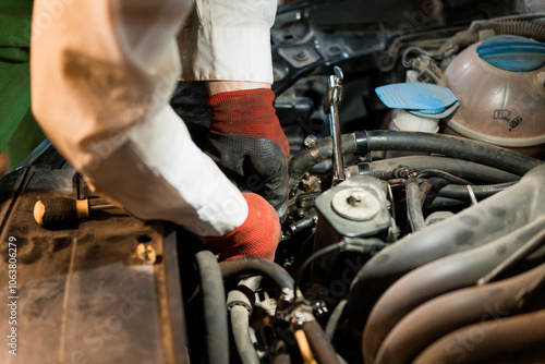 Mechanic Repairing Engine with Tools Under Hood of a Car