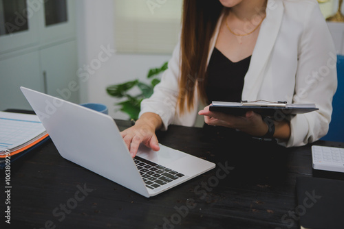 Asian businesswoman, focused , sits at ablack wooden table. Surrounded by notes , she strategizes her next move, embodying confidence and professionalism in her workspace. photo