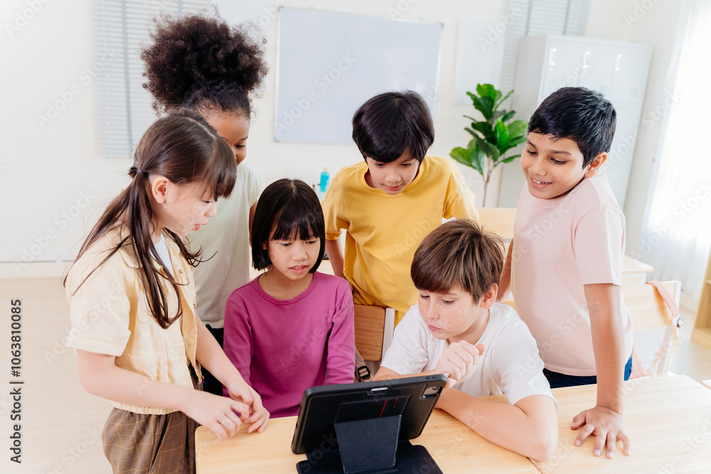 Fototapeta premium Diverse elementary students collaborate on digital tablet in modern classroom. Multicultural group engages in interactive learning, showcasing inclusive education and technological integration