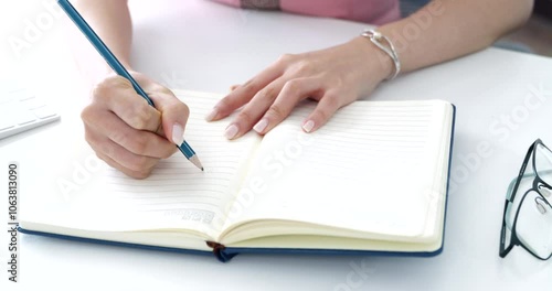Close-up of a woman’s hand writing her daily to-do list in a book. Ideal for content on productivity, organization, lifestyle, and self-management, task prioritization and effective work habits