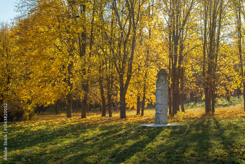 The park in autumn is filled with bright yellow leaves, stands a majestic idol sculpture made of stone, this stone sculpture is full of symbolism and depth The park in autumn is filled with bright yellow leaves, stands a majestic idol sculpture made of stone, this stone sculpture is full of symbolism and depth