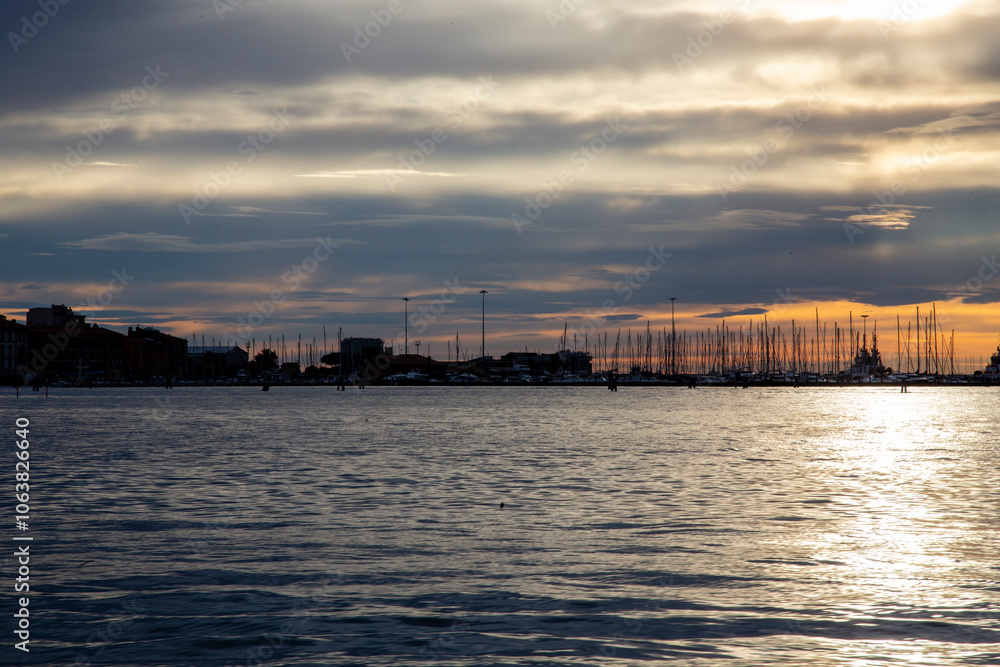 Red sunset over the lagoon, with docked boats and the outline of the town, backlit on the sea, Chioggia, Venice area, Italy Red sunset over the lagoon, with docked boats and the outline of the town, backlit on the sea, Chioggia, Venice area, Italy