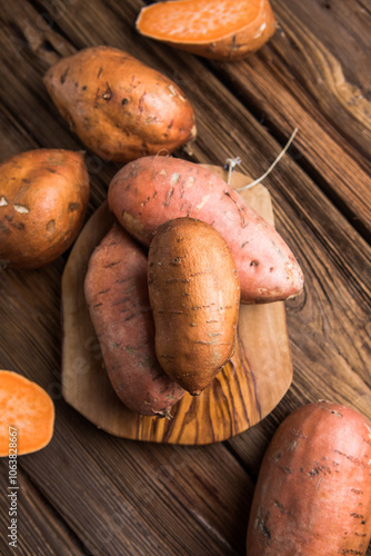 Raw sweet potatoes on wooden background closeup