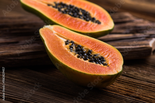 A ripe papaya cut in half on a wooden chop block. photo