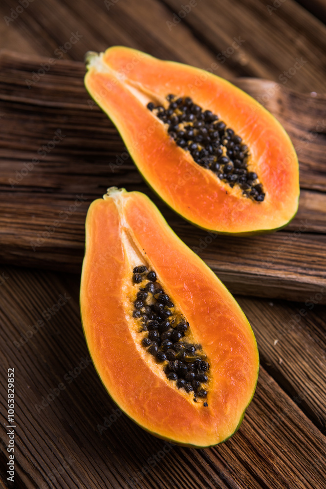 A ripe papaya cut in half on a wooden chop block. A ripe papaya cut in half on a wooden chop block.