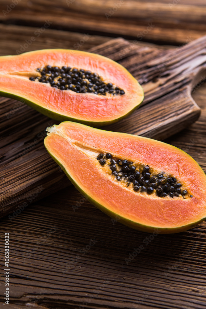 A ripe papaya cut in half on a wooden chop block. A ripe papaya cut in half on a wooden chop block.