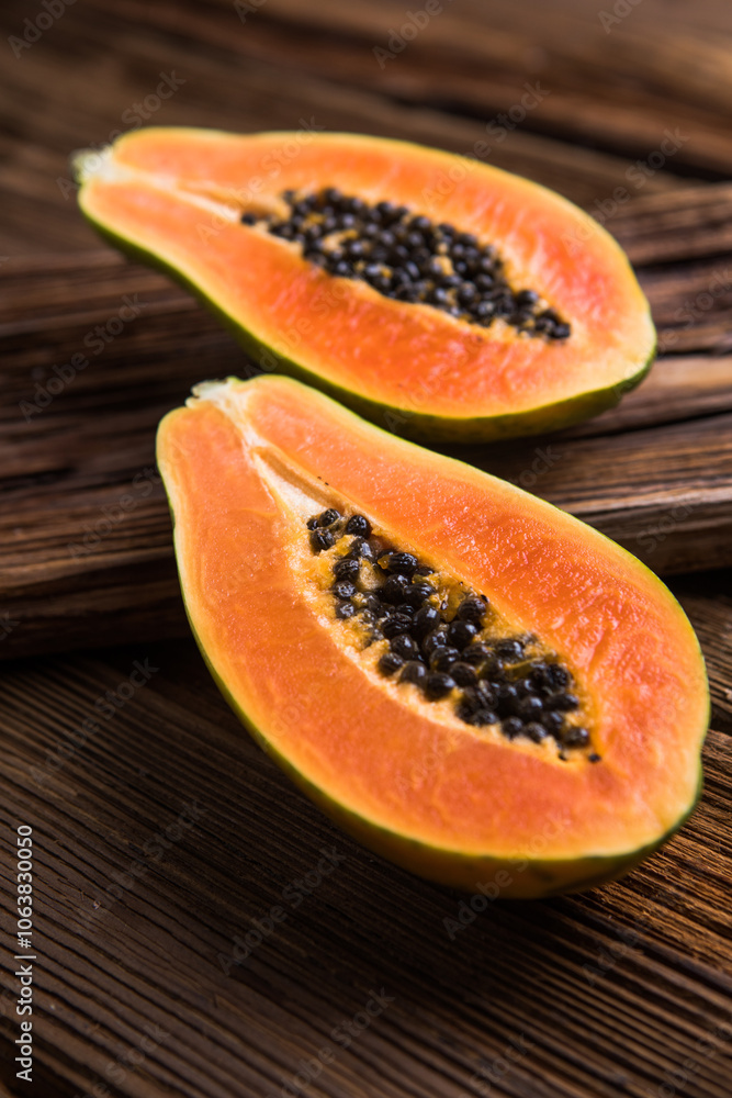A ripe papaya cut in half on a wooden chop block. A ripe papaya cut in half on a wooden chop block.