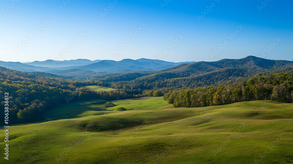 Naklejka premium Sweeping drone footage of rolling hills and distant mountains under a clear blue sky