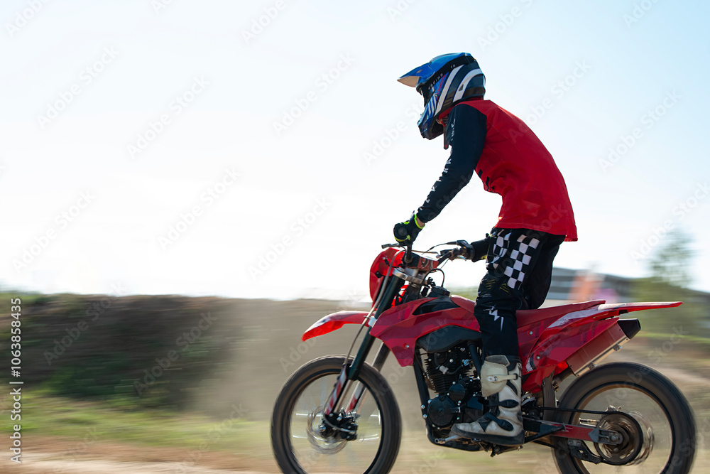 Motocross racing. A motorcyclist wearing protective clothing and a helmet rides a motorcycle standing up at high speed. A boy rides a motorcycle off-road. Motocross racing. A motorcyclist wearing protective clothing and a helmet rides a motorcycle standing up at high speed. A boy rides a motorcycle off-road.