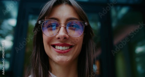 Attractive Caucasian woman looking at sky before glancing at camera and smiling. Wearing big round glasses for better vision. Portrait concept. Manager spending time outside during lunch break.