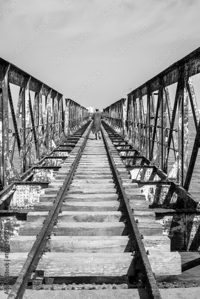 Fototapeta premium Un pont de chemin de fer traverse une rivière dans la ville de Saint Louis du Sénégal en Afrique de l'Ouest