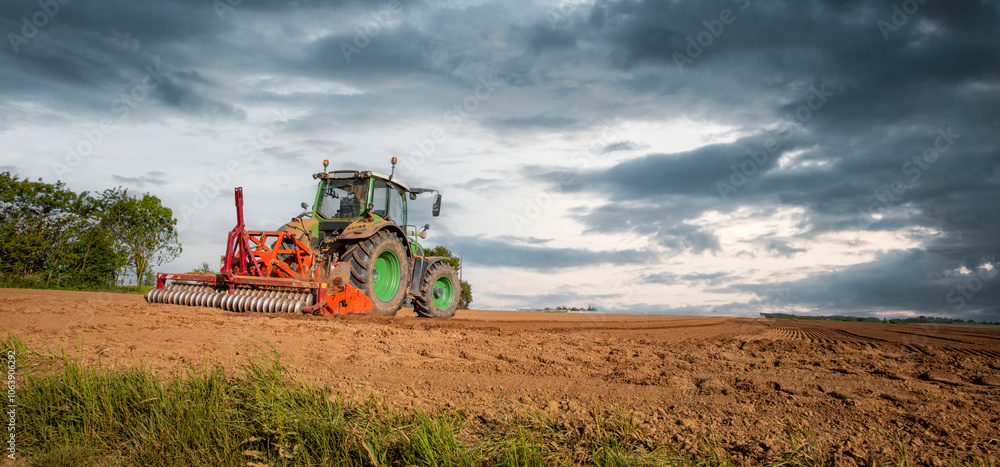 Obraz premium Tracteur labourant les champs dans la campagne de France au printemps.