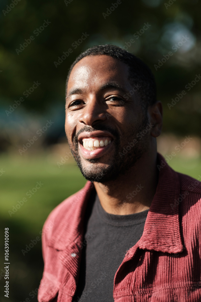 Portrait of smiling young man wearing red corduroy jacket in park Portrait of smiling young man wearing red corduroy jacket in park