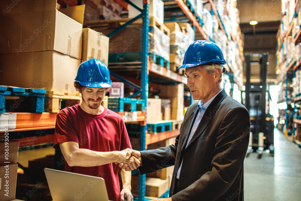 Warehouse worker discussing logistics with manager over a laptop Warehouse worker discussing logistics with manager over a laptop