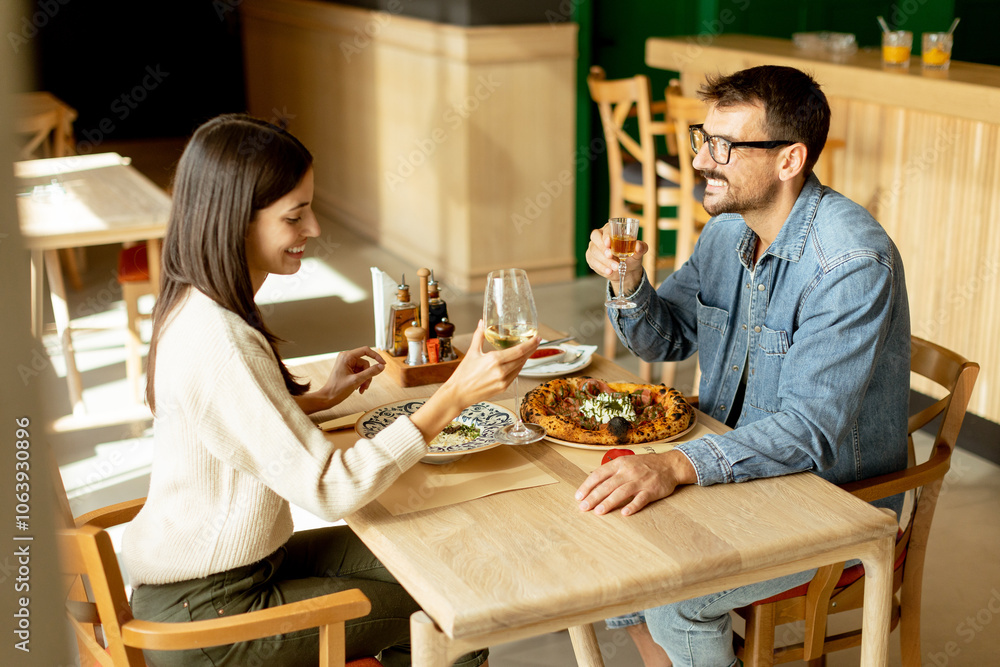 Couple enjoying a romantic dinner together in a cozy restaurant, celebrating with a toast over delicious cuisine on a warm evening Couple enjoying a romantic dinner together in a cozy restaurant, celebrating with a toast over delicious cuisine on a warm evening
