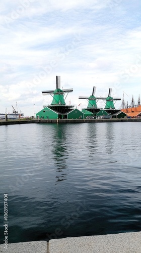 Traditional Dutch windmills reflect in tranquil waters beneath a stunning sky over a picturesque landscape