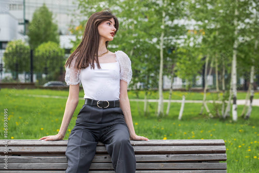 Young woman sitting on a bench in a summer park Young woman sitting on a bench in a summer park