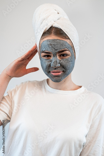 portrait of young woman getting facial care clay or mud mask isolated on white