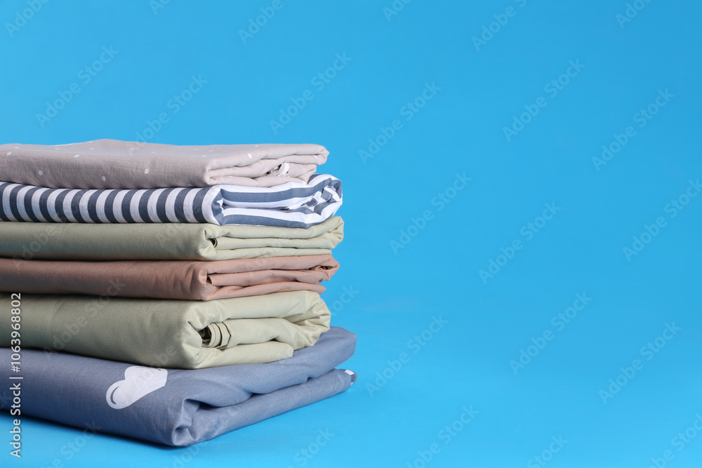 Stack of clean bed sheets on blue background. Space for text Stack of clean bed sheets on blue background. Space for text