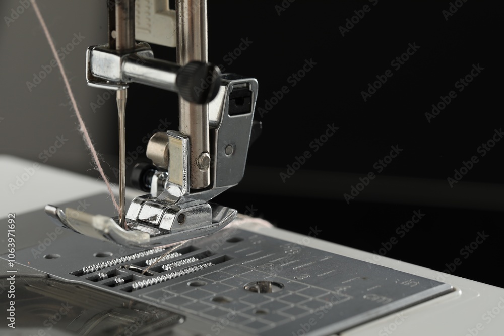 Fototapeta premium Sewing machine with thread on dark background, macro view. Space for text