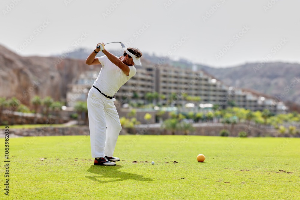 Fototapeta premium The golfer hits the golf ball with the Drive in his hand, on the tee.