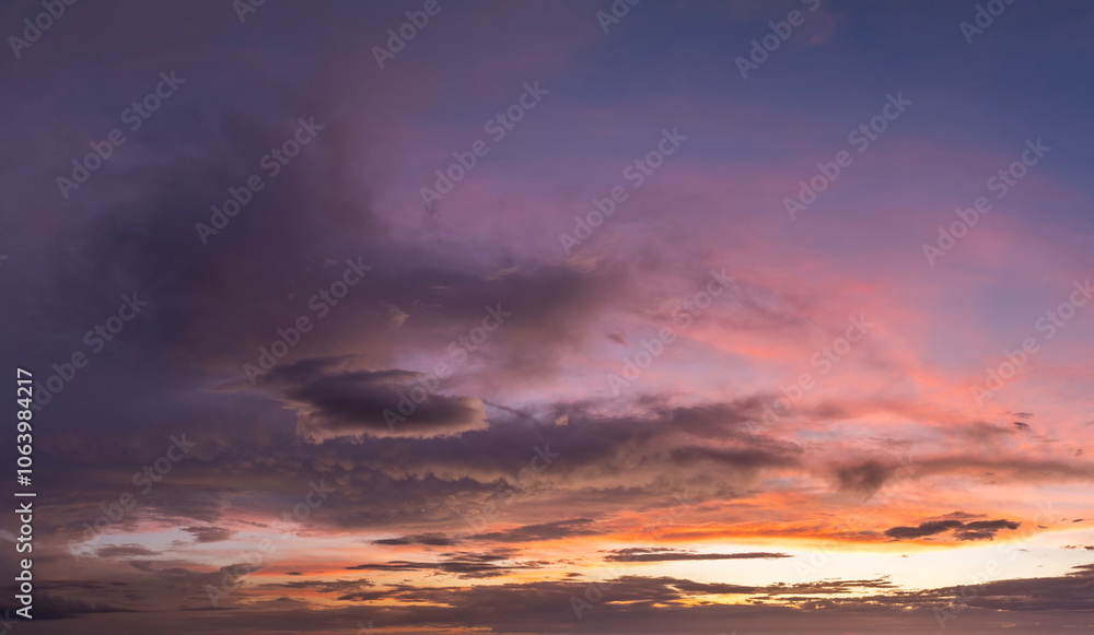 Colorful sunset sky with setting sun behind vivid orange and yellow clouds Colorful sunset sky with setting sun behind vivid orange and yellow clouds