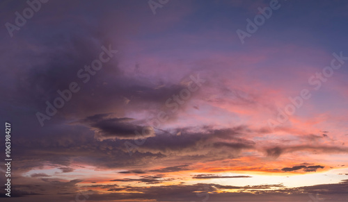 Colorful sunset sky with setting sun behind vivid orange and yellow clouds