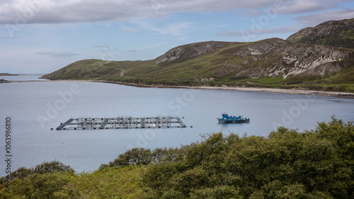 Salmon farm in the round basins and a blue fishing boat on the northwest coast of beautiful Scotland