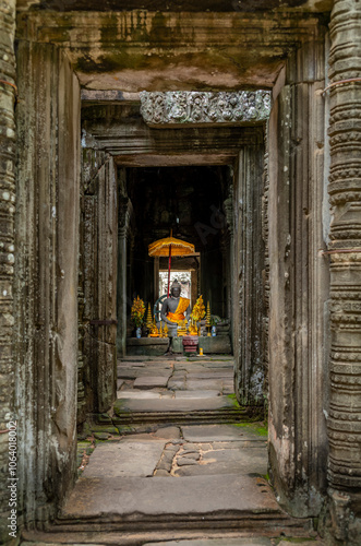 A statue of Buddha and offering at the Banteay Kdei temple in Cambodia photo