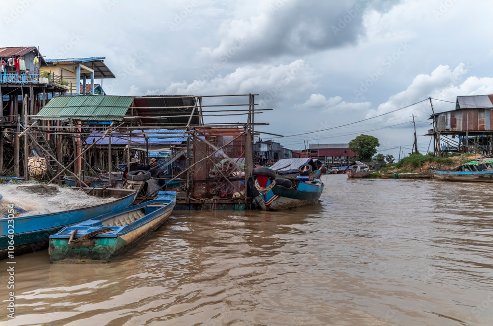 The colorful village of Kampong Phluk with houses on stilts, fishing boat and fishing nets near Siem Reap in Cambodia The colorful village of Kampong Phluk with houses on stilts, fishing boat and fishing nets near Siem Reap in Cambodia