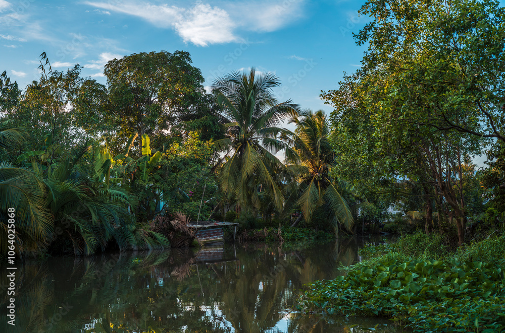 Palm trees, boats and buildings reflecting on the quiet waters of the canals in Can Tho in Vietnam Palm trees, boats and buildings reflecting on the quiet waters of the canals in Can Tho in Vietnam