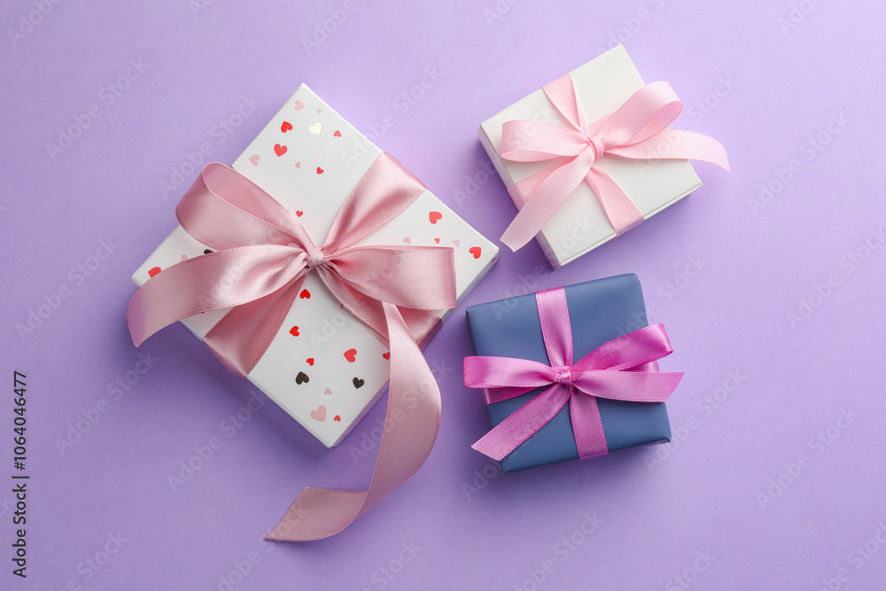 Fotografie Beautiful gift boxes with pink bows on violet background, flat lay